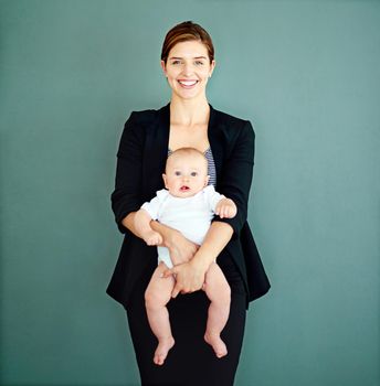 Balancing motherhood and ambition. Studio shot of a successful young businesswoman carrying her adorable baby boy.