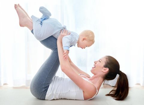 Mommy and me exercises. Shot of a young woman working out while spending time with her baby boy.