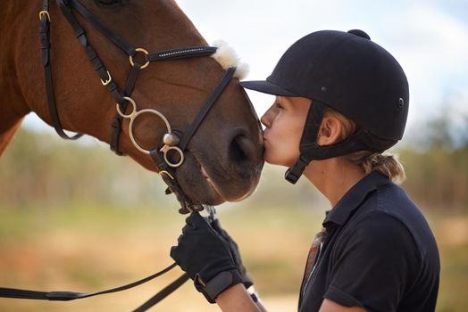 There is a bond between horse and rider. A young female rider being affectionate with her chestnut horse.