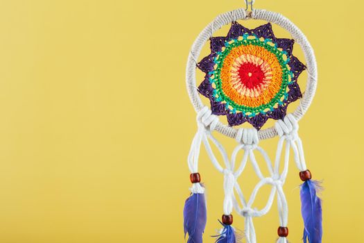 Handmade amulet dream catcher on a yellow background, protecting the sleeper