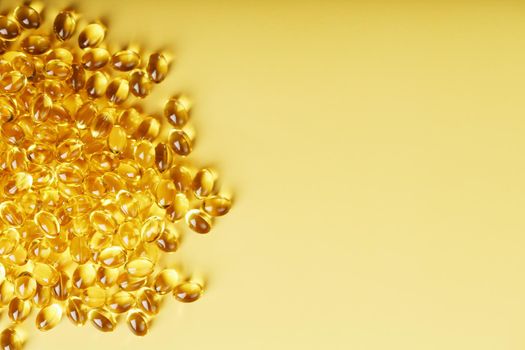 Pile of golden capsules of vitamin D3 on a yellow background with free space