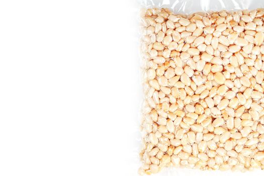 Kernels of peeled pine nuts in vacuum packaging on a white background