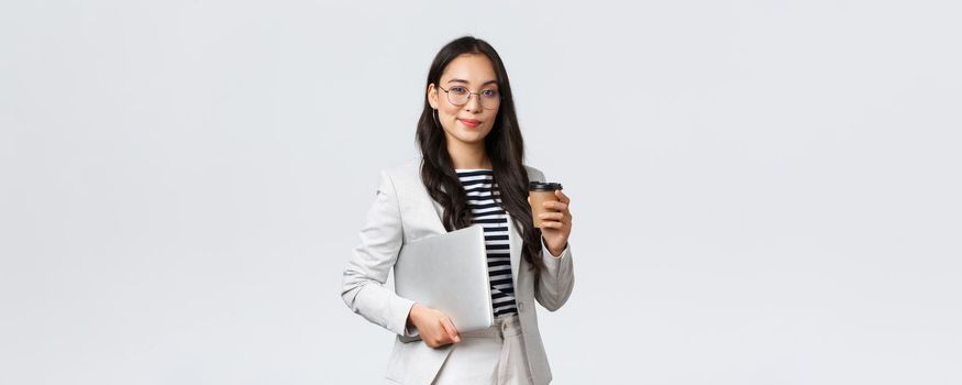 Business, finance and employment, female successful entrepreneurs concept. Confident good-looking businesswoman in glasses and suit drinking takeaway coffee and carry work laptop