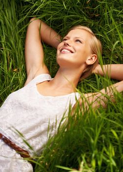 Relaxed in natures calm embrace. An attractive young woman lying in an open green field.