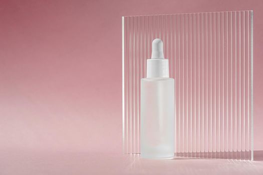Serum oil with collagen and peptide in white transparent bottle with dropper on pink backdrop with acrylic ribbed sheet. Skincare treatment skincare mockup packaging liquid cosmetic product.