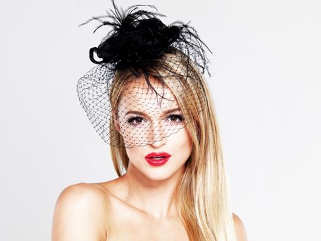 Timeless beauty. A portrait of a glamourous blonde woman wearing a feather hat and red lipstick while isolated on white.