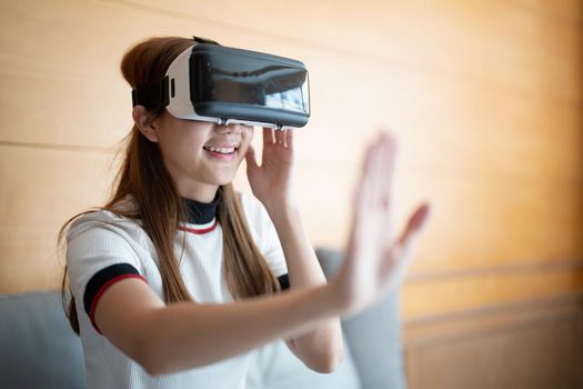 Excite asian woman playing online game with vr glasses and controller at her home