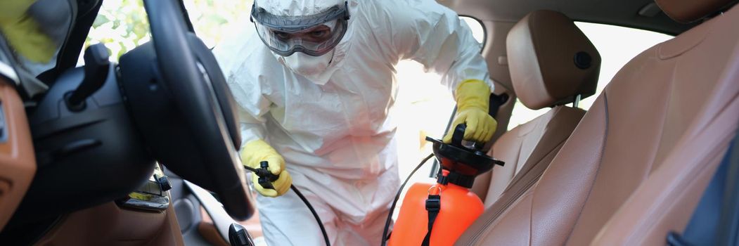 Man in protective suit cleaning car
