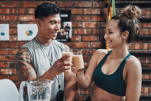 Cheers to a fit and healthy life. Cropped shot of two young sportspeople making a toast with milkshakes while working in a gym.
