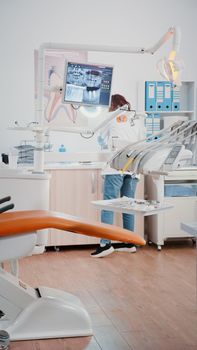 Vertical video: Stomatologist using chair with tools for dental care in dentistry cabinet. Dentist preparing teethcare equipment for examination in office designed for dentistry checkup