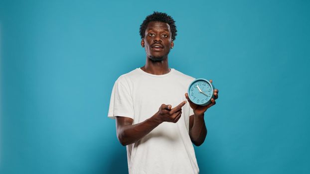 Casual person pointing at time on wall clock for hour and minutes