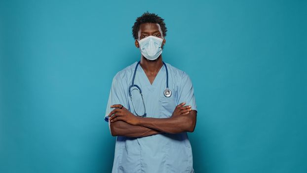 Man nurse standing with crossed arms while wearing face mask