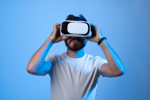 Future technology, gaming, entertainment and people concept - happy young man with virtual reality headset or 3d glasses playing video game in metaverse