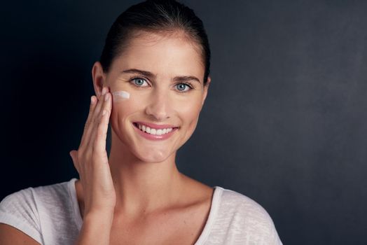 Healthy skin thanks to a great moisturizing routine. Studio portrait of an attractive young woman applying moisturizer to her face.
