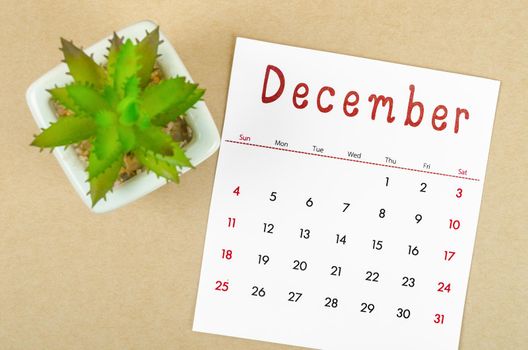 December 2022 calendar with plant pot on brown paper background.