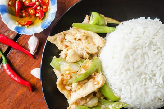 Chicken stir fried with green chilli and steamed rice in black dish. Thai food.
