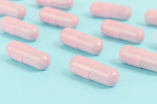 Pink capsule pills on blue background.