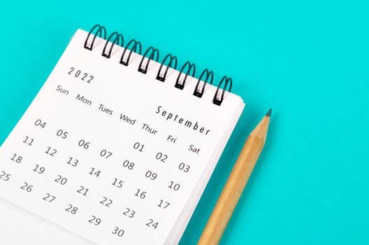 September 2022 desk calendar with wooden pencil on light blue background.