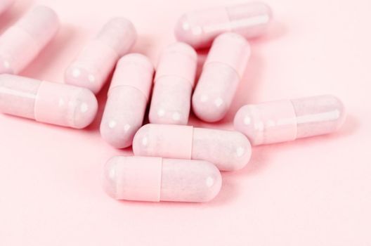 Pink capsule pills on pink background 