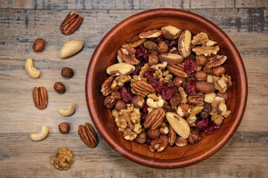 Mixed nuts and dried fruits in wooden bowl on wood background, copy space