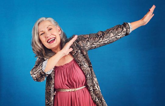 Shes hitting the dab. Portrait of a funky and cheerful senior woman dancing in studio against a blue background.