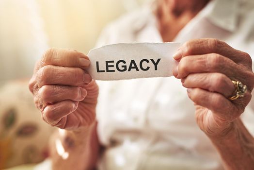 May your legacy last forever. Cropped shot of an elderly woman holding a piece of paper with the word legacy on it.