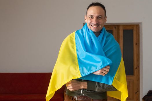 Handsome man with flag of Ukraine at home.