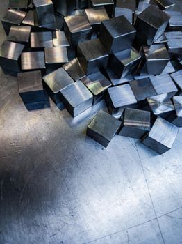 pile of small machined shiny steel cubes on metal surface
