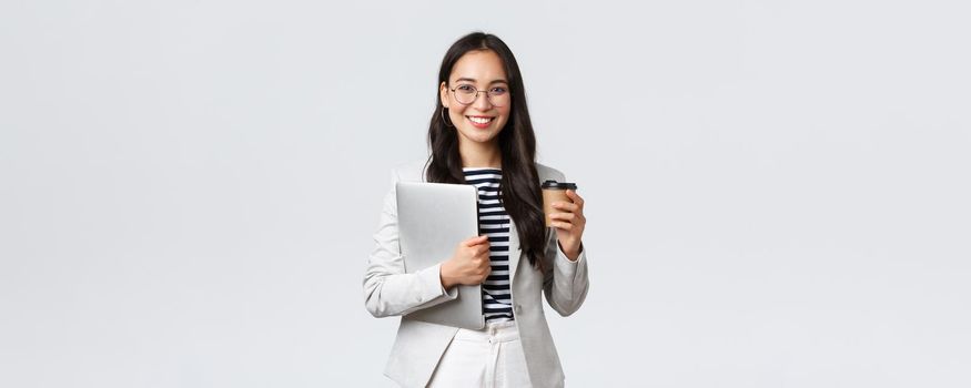 Business, finance and employment, female successful entrepreneurs concept. Confident good-looking businesswoman in glasses and suit drinking takeaway coffee and carry work laptop