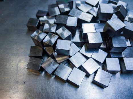 pile of small machined shiny steel cubes on metal surface