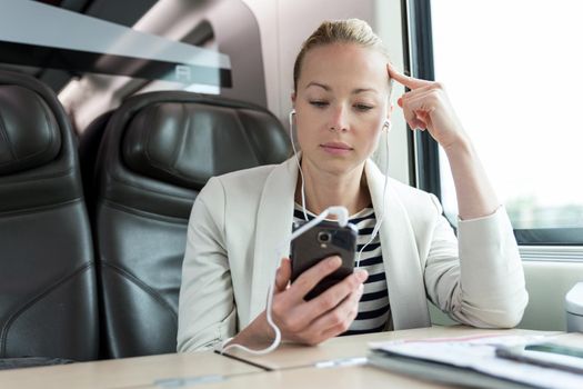 Businesswoman communicating on mobile phone while traveling by train.
