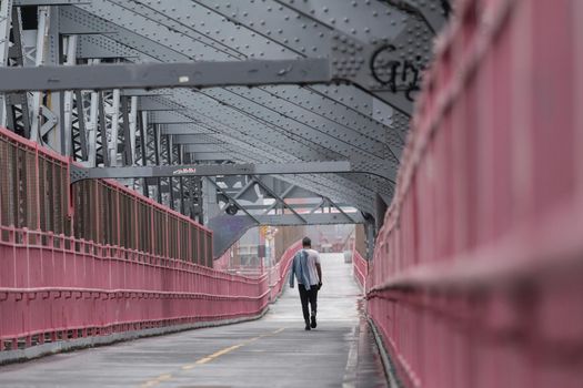 Solo casual man walking the cycling lane on Williamsburg Bridge, Brooklyn, New York City, USA