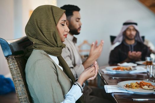 Giving thanks for a bountiful feast. Shot of a muslim family praying before they break their fast.