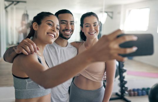 Shot of three young athletes taking a selfie while standing together in the gym.