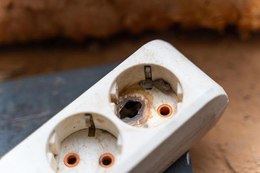 Melted outlet hole. Burnt contact on the network pilot close-up. Short circuit in euro socket