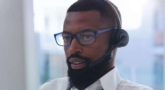 Give me a sec to check what the issue is. Shot of a young businessman wearing a headset while working in an office.