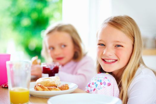 Smiling little girl with her sister having breakfast. Portrait of a smiling little girl with her sister having breakfast.
