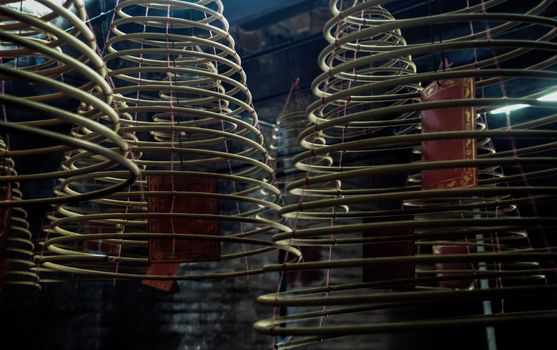 Multiple large yellow incense coils hanging in stacks from the Ceiling in a Chinese shrine. Large Bell Shaped Spiral Incense Coils, Focus and blur.