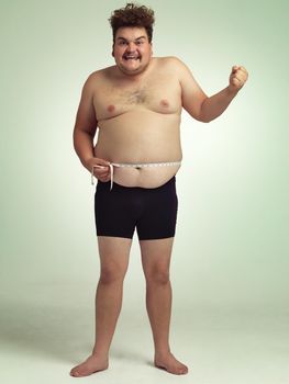 Losing weight and feeling great. Shot of an overweight man measuring himself.