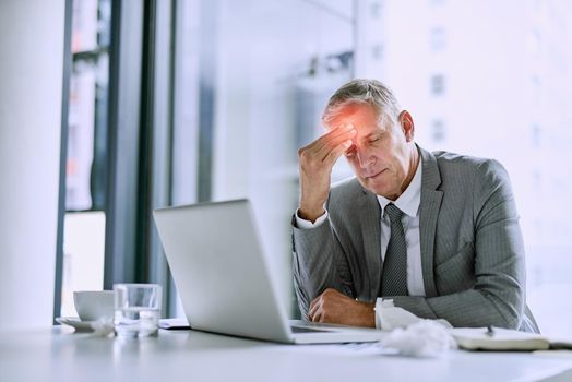 Its a stress-related headache. Cropped shot of a mature businessman suffering with a headache in the office.