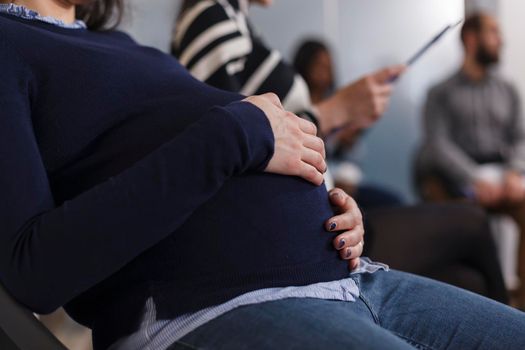 Close up of pregnant job recruiter holding hand on belly bump