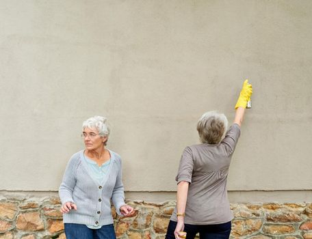 Hurry up. Shot of mischievous pensioners spray-painting graffiti on a wall.