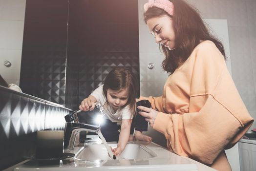 happy family and health. mother and daughter baby girl brushing their teeth together. mom holds a little jar of cream