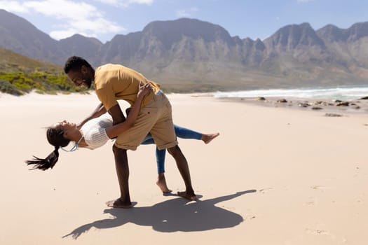 African american couple having fun dancing on a beach by the sea