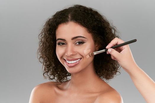 Make up is all about applying it correctly. Studio shot of a beautiful young woman applying foundation with a make up brush against a gray background.