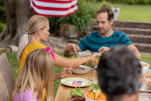 Caucasian man serving family before eating meal together in garden