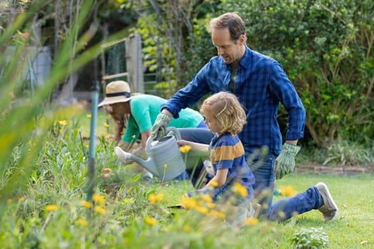 Caucasian father and son in garden watering plants and gardening with their family. happy three generation family spending time together at home.