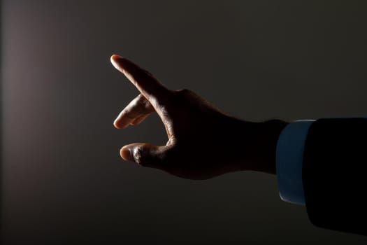 Close up of hand of businessman touching invisible screen against dark background