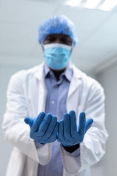 Portrait of african american male doctor wearing face mask surgical cap and latex gloves