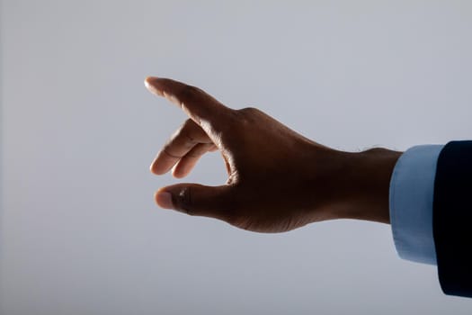 Close up of hand of businessman touching invisible screen against grey background